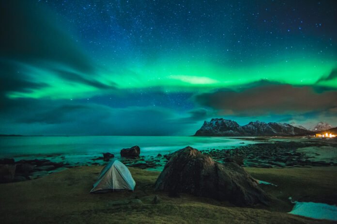 Aurora borealis over a tent on Uttakleiv Beach in the Lofoten Islands, Norway